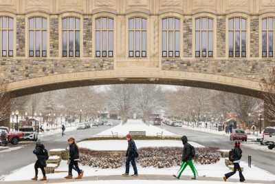 students walking in front of Torgersen Bridge on a snowy day