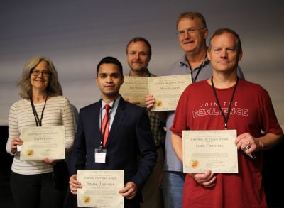 Several recipients of the 2024 Employee Awards & Recognition stand together holding their certificates and smiling for a group photo.