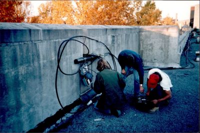 (L to R) Phil Benchoff, Brian Jones, and Tom Tompkins mount LocalNet equipment on the roof of Norris Hall, using a discarded piece of road barrier pipe to secure the components.