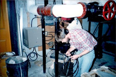 Brian Jones (front) and Tom Tompkins (back) work in the Burruss Hall mechanical room. Note the LocalNet power supply mounted next to the plywood distribution board.
