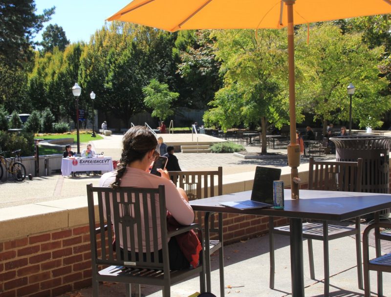 Student hunched over a laptop while talking on the phone