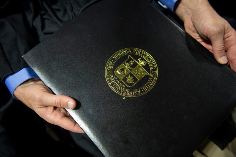 Close-up of hands holding diploma with gold Virginia Polytechnic Institute and State University seal. 