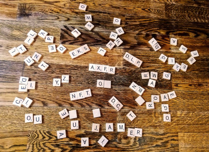 scrabble tiles scattered on a hardwood floor spelling out acronyms