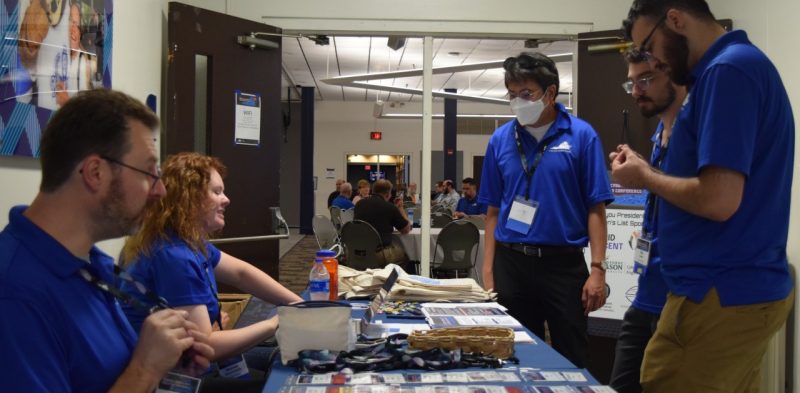 People standing at a table handing out name badges.